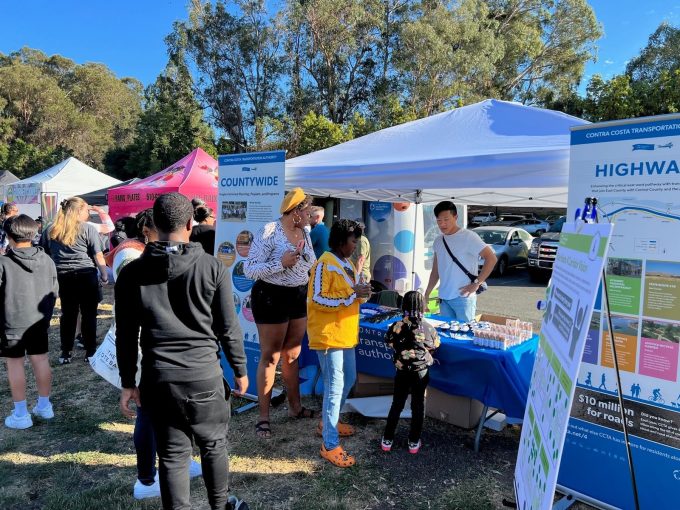 People engaging with informational booths about mobility and transit at an outdoor event.
